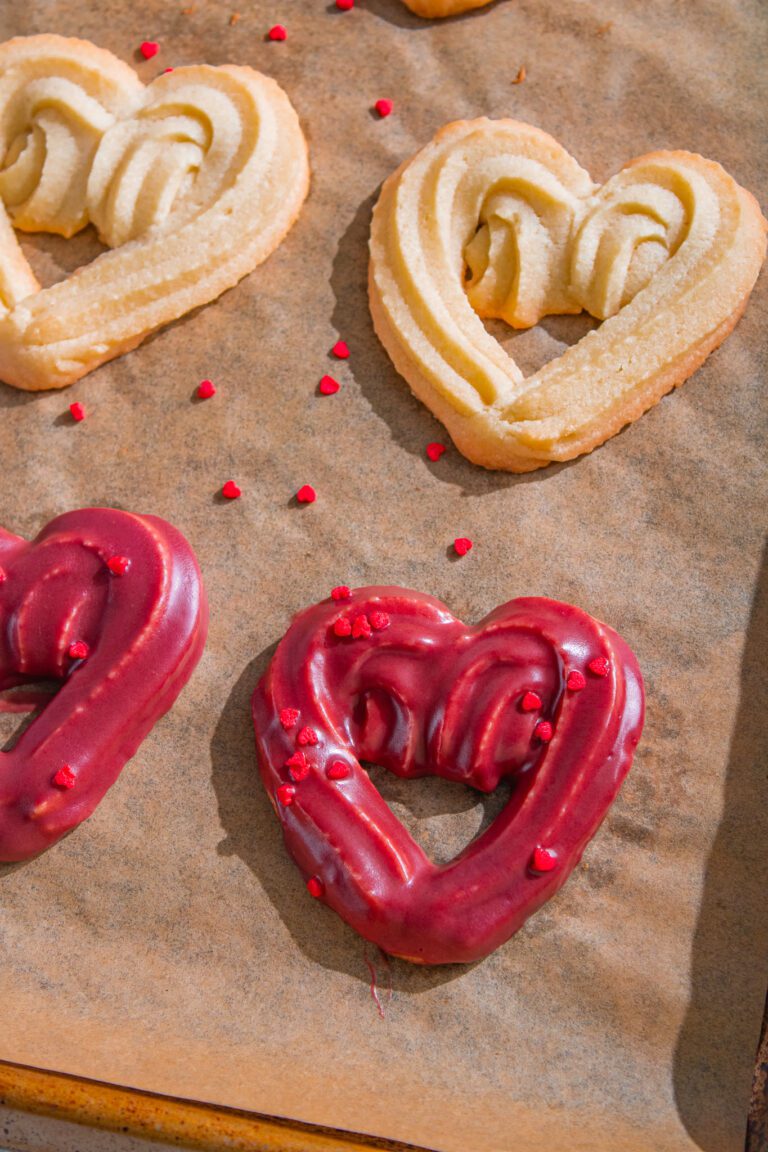 Eggless chocolate-dipped heart cookies stacked on a tray