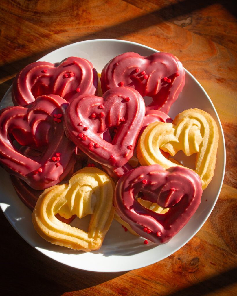 Eggless chocolate-dipped heart cookies stacked on a plate
