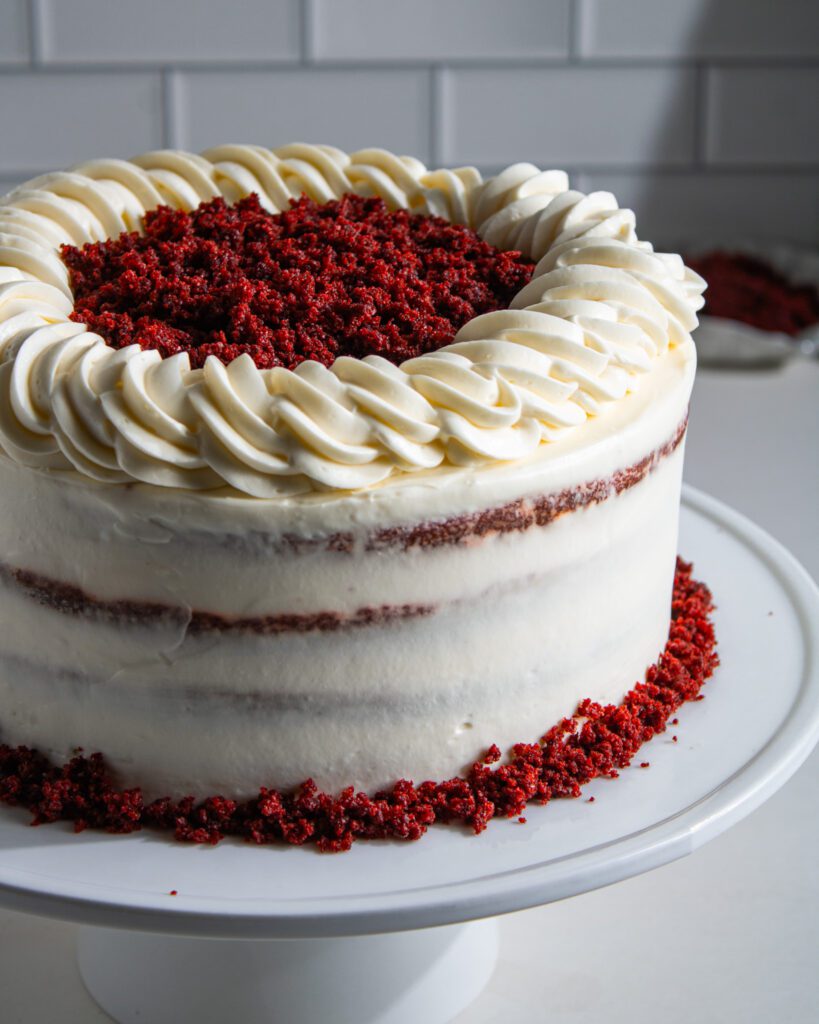Eggless red velvet cake with whipped cream cheese frosting sliced on a cake stand