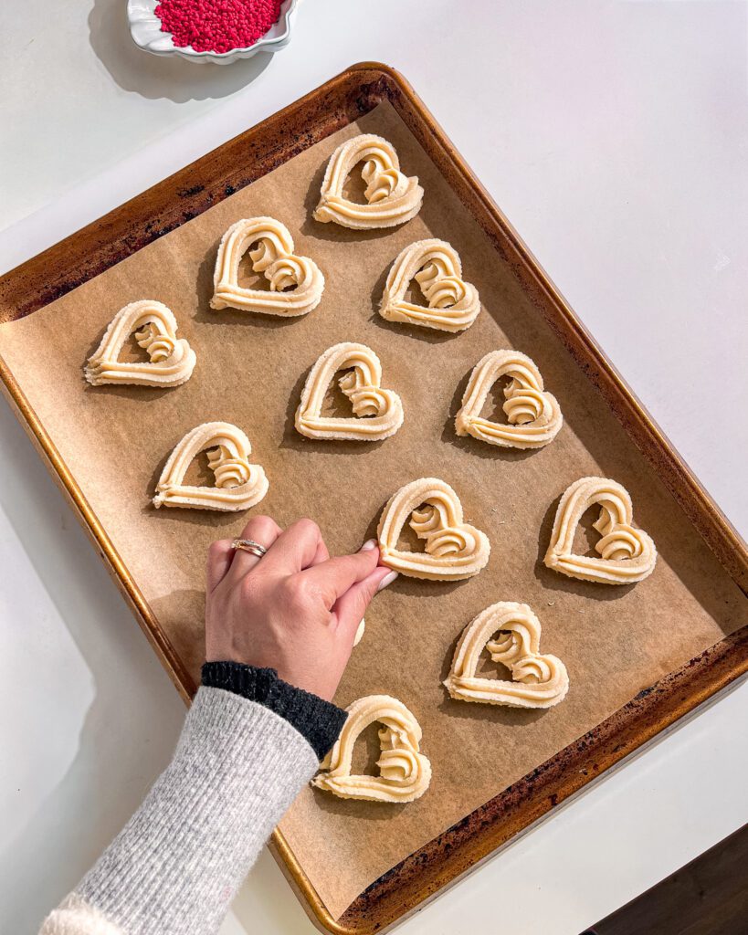 Hand-piping eggless butter cookie dough into heart shapes