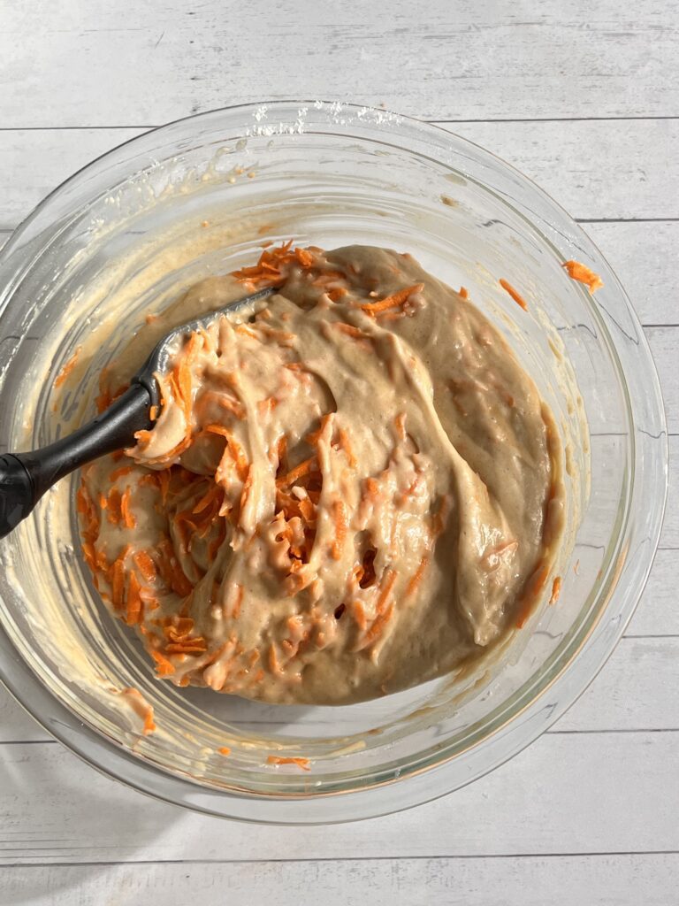 mixing grated carrots into eggless carrot cake batter