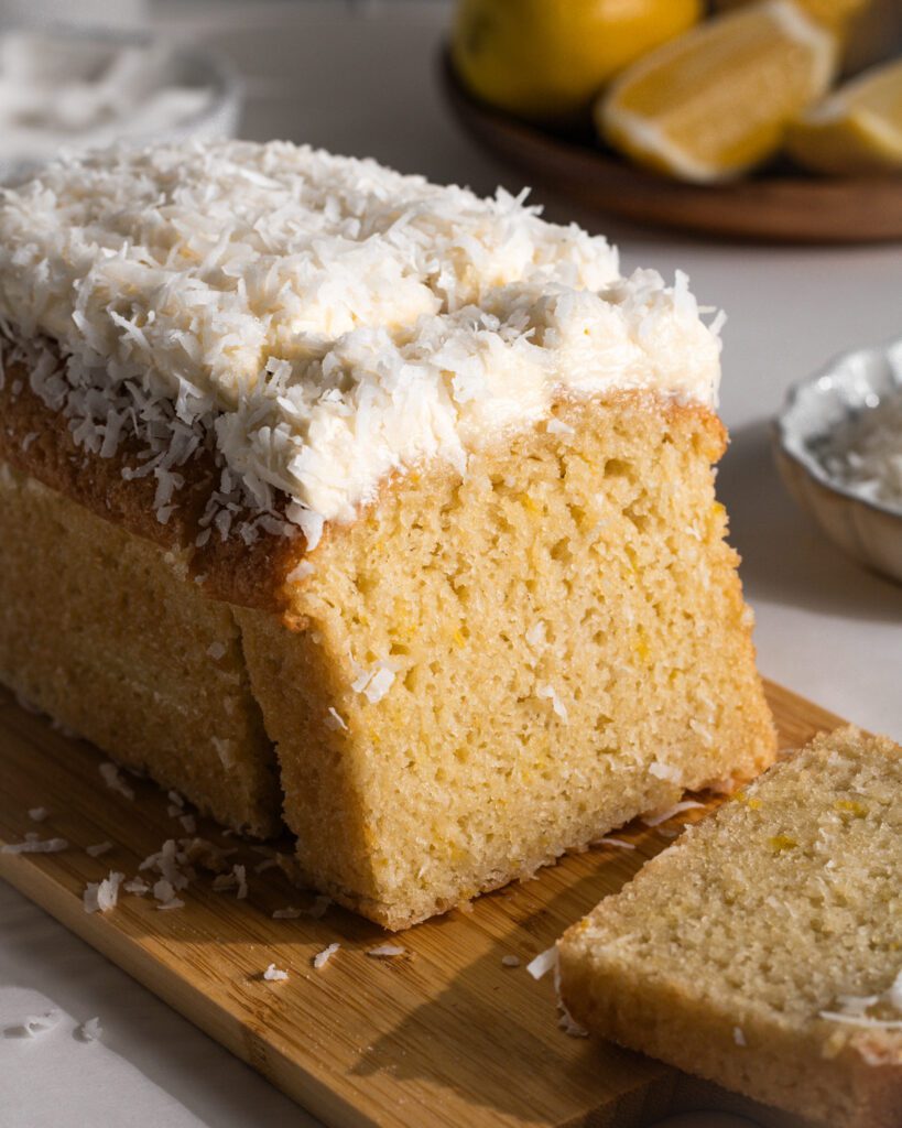 Slice of soft eggless lemon loaf cake with creamy frosting